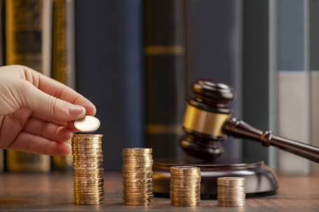 Hand stacking coins beside a judge’s gavel to represent contingency fees in personal injury cases